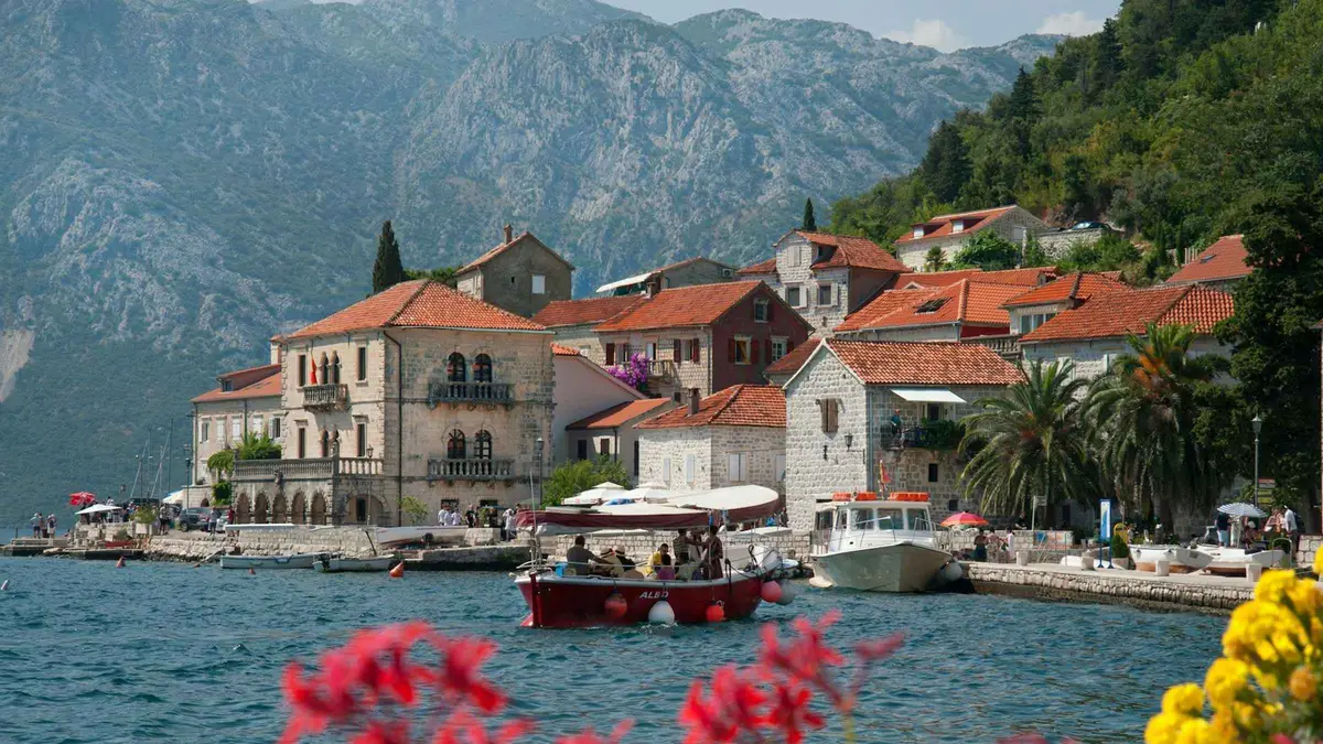 Boat cruising past Our Lady of the Rocks toward Perast in the Bay of Kotor